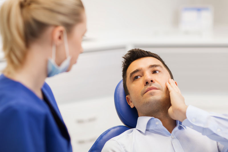 a dental patient experiencing tooth pain preparing for a wisdom tooth extraction.