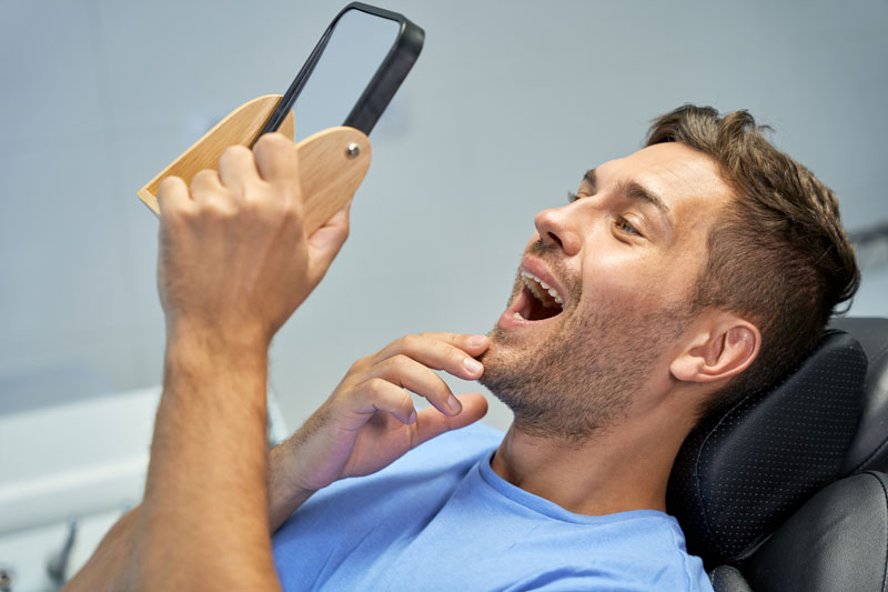 guy looking through mirror at teeth